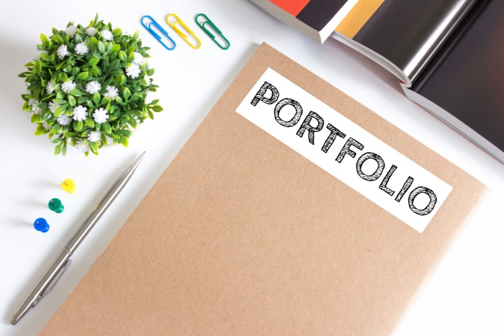 A teacher portfolio lays on a desk next to a pen and paperclips.