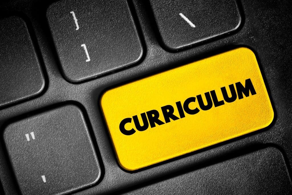 A close up of a keyboard with a key on it that says “curriculum” and is painted yellow representing curriculum implementation.
