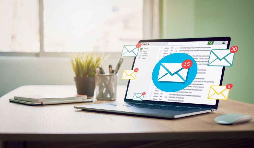 A computer sits on a work desk, showing email notifications.