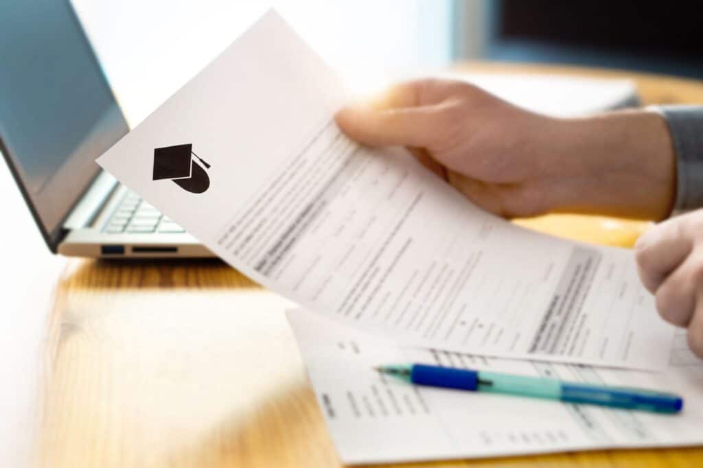 A close-up of a pair of hands holding a printed graduate school application.