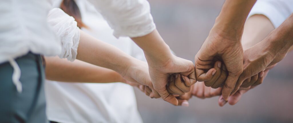 Workers all fist bump, representing teamwork.