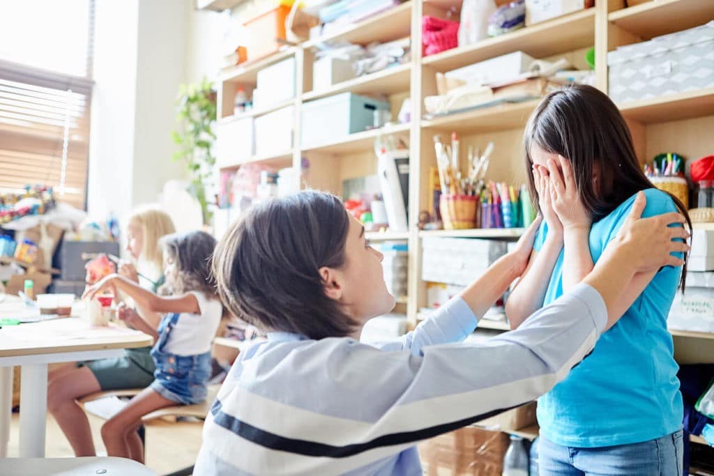 Teacher consoling a crying student in art class.