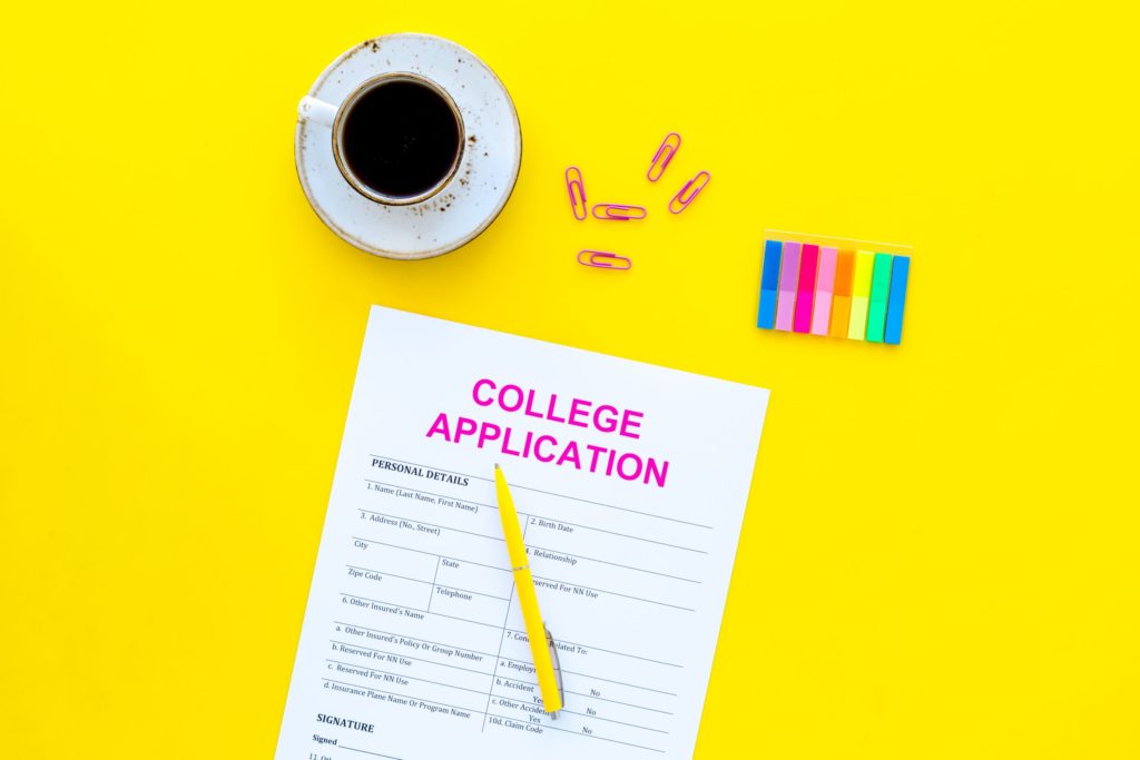 A portrait of an empty college application sitting near a coffee cup, pencil, and paper clips.