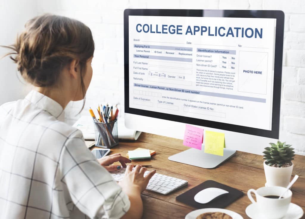 Woman filling out a college application at a desktop computer.