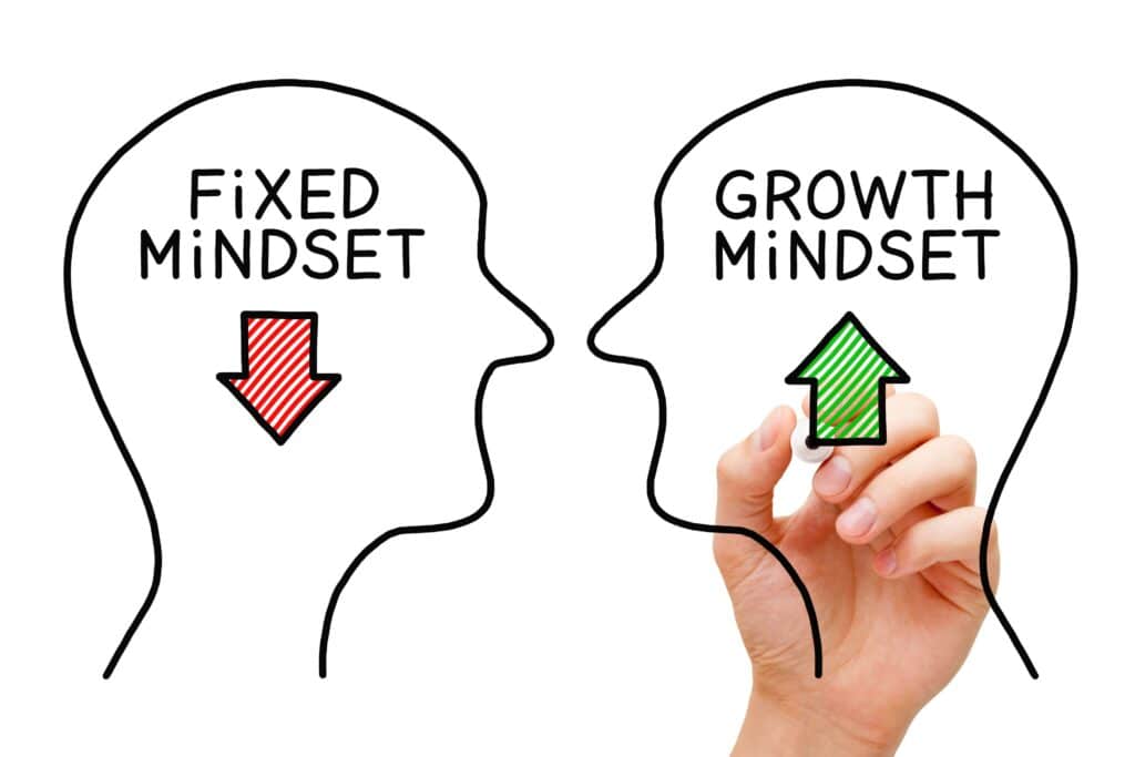 A whiteboard drawing of two outlines of a head with one up arrow and one down arrow. The up arrow represents growth mindset.